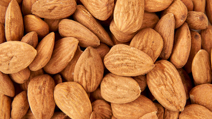 Background of big raw peeled almonds situated arbitrarily.