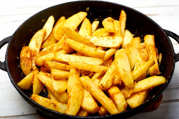 Cooking fried potatoes in a pan. Sliced potato with spices.