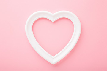 Frame of white heart shape on light pink table background. Pastel color. Love and happiness concept. Empty place for cute, emotional, sentimental text, quote or sayings. Closeup. Top down view.