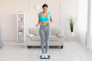 Fototapeta na wymiar Woman Measuring Waist Standing On Scales Slimming At Home, Full-Length