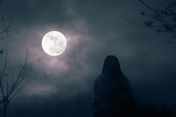 Silhouettes of dry trees against night sky with clouds and Woman stands to watch the full moon in the night alone, nature background © fon