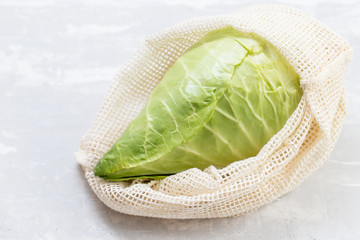 fresh green cabbage in cotton bag on ceramic background