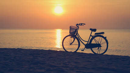 Fototapeta premium Silhouette of bike and sunrise at the beach,Vintage and Dark tone,Alone