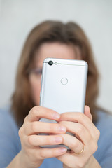 woman holds gray phone in the face