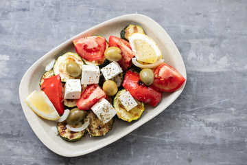 salad with fresh and grilled salad on white dish on gray ceramic background