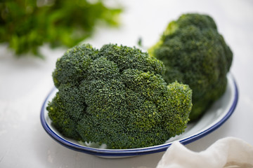 fresh broccoli on white dish on ceramic background