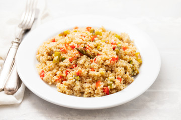 quinoa with vegetables on white plate on ceramic background
