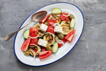 salad with fresh and grilled salad on white dish on gray ceramic background
