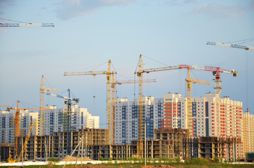 Naklejka premium Inside place for many tall buildings under construction and cranes under a blue sky working on place with tall homes