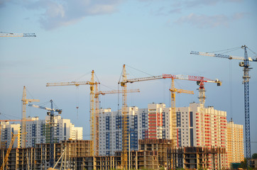 Fototapeta premium Inside place for many tall buildings under construction and cranes under a blue sky working on place with tall homes