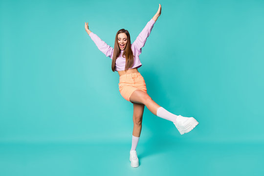 Full body photo of funky cool lady raise leg arms enjoy youth party dancing wear purple cropped sweater naked belly orange skirt shoes long socks isolated teal color background