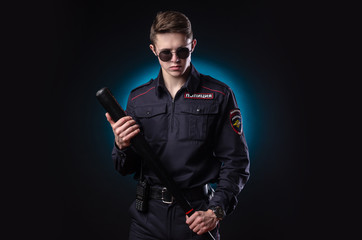 Fototapeta na wymiar handsome guy in a police officer's uniform with a baseball bat. english translation 