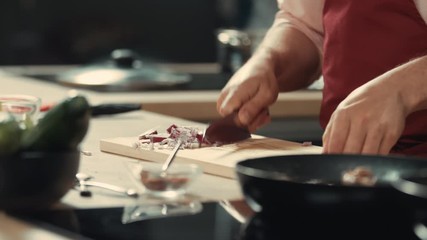 CU ZOOM IN Chef cuts an onion on a wooden board