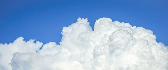 Fluffy clouds across blue sky background 