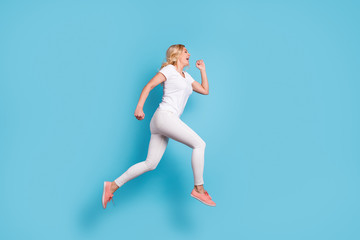 Fototapeta na wymiar Full length profile photo of attractive funny crazy lady jump high up running speed rushing shopping center wear casual white s-shirt pants footwear isolated blue color background