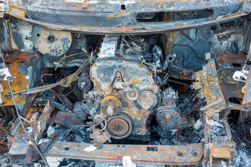 The burned out wreckage of an old van in a road layby 