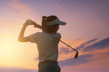 Young Women Asia player golf swing shot on course with sunset sky twilight background. exercise and health concept. Golf practice to be a professional golfer