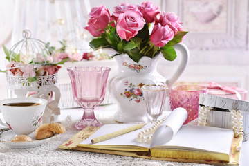 bouquet of pink roses in jug on the table with coffee and notebook