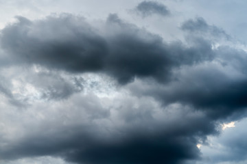 Fototapeta premium Bad weather with the sky completely covered by gray and black rain clouds placed in several layers, dark atmosphere with nimbus and cumulus clouds. Climate change causes extreme weather events.
