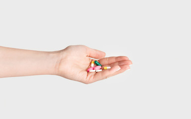 Virus treatment or suicide concept. Girl holding pile of pills on white background, closeup