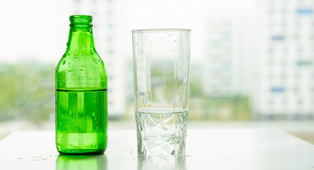 transparent glass of water with air bubbles green glass bottle