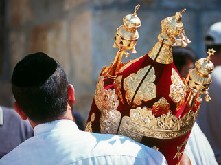 Jewish man in black kippah carrying a Torah scroll in a beautifully ornate red case with golden bells and crowns (rimmonim) and other decorations - Simchat Torah; Western/Wailing Wall, Jerusalem - obrazy, fototapety, plakaty