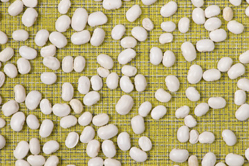 White beans spread on a lemon-colored napkin. Top view.