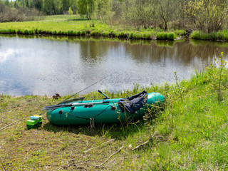 landscape with green rubber boat on the river shore, fisherman's equipment, Seda River, Latvia