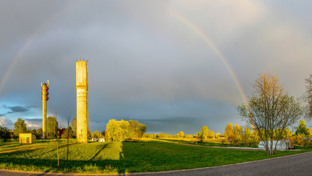 Panoramic View Of Two Water Towers And A Rainbow