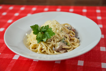 Spaghetti with cheese and meat on a white plate garnished with parsley
