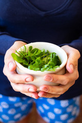 Fresh green rucola herb grass spice in woman hands.