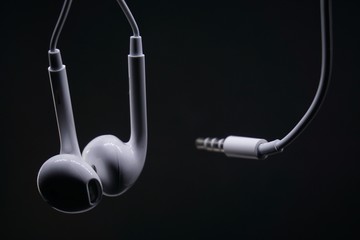 White earphone with black background. Earphone and audio jack with black background.