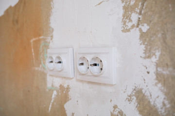 White outlets on concrete wall during repair. Installation of sockets during repair in fresh cement empty walls