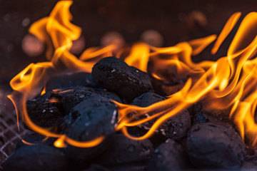 Grill briquettes that are burning and waiting to be glowed for grilling, Briquettes are made from lignite, peat, charcoal or coal stub - obrazy, fototapety, plakaty