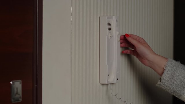A woman answers a call to the intercom, picks up the phone, launches a guest