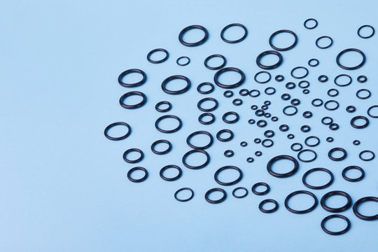 Black hydraulic and pneumatic o-ring seals of different sizes a blue  background. Rubber rings. Sealing gaskets for hydraulic joints. Rubber sealing rings for plumbing. Top view