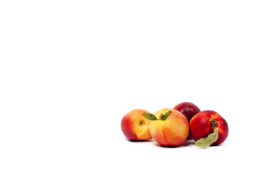 four ripe yellow and red nectarines with green leaves isolated on a white background