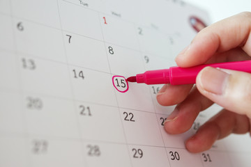 Hand with pen mark at 15th on calendar date