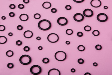Black hydraulic and pneumatic o-ring seals of different sizes a pink  background. Rubber rings. Sealing gaskets for hydraulic joints. Rubber sealing rings for plumbing. Top view