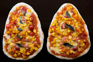 Homemade naan pizzas topped with bell peppers, cherry tomatoes, corn and basil leaves