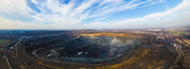 Wide panorama of open-pit mine aerial view with big trucks working