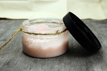 Natural scrub in container with open lid on grey background