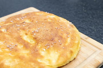 Italian round focaccia with salt on a wooden cutting board. Homemade focaccia with salt and flavorful. Traditional homemade food similar to pizza