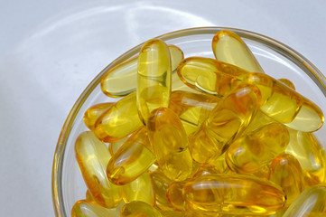 Fish oil capsules on a glass plate. A lot of vitamin omega 3. Close-up.