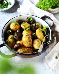 Baked young potatoes with mushrooms in a bowl on a gray background