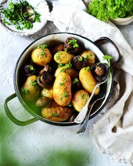 Baked young potatoes with mushrooms in a bowl on a gray background