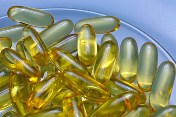 Fish oil capsules on a glass plate. A lot of vitamin omega 3. Close-up.