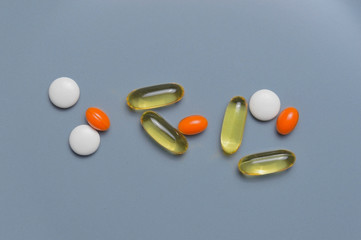 multi-colored pills and vitamins in capsules on a gray background. top view