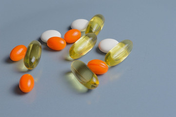 multi-colored pills and vitamins in capsules on a gray background. top view