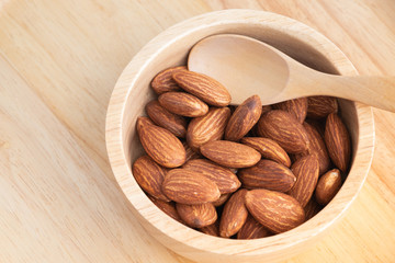 almonds in a wood bowl on grained wood background